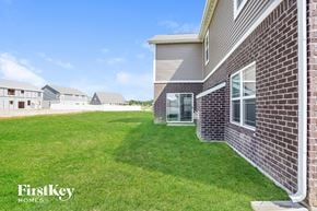 New Palestine house for rent - A brick house with a grassy lawn in front and a clear blue sky above.