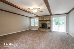 Carmel house for rent - A spacious room with a fireplace and a ceiling fan.