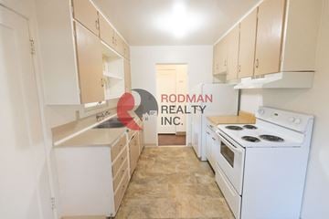 Longview apartment for rent - A kitchen with white appliances and cabinets is shown with a sign that says Rodman Realty Inc.