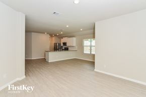 San Antonio house for rent - an empty living room and kitchen with white walls and wood flooring