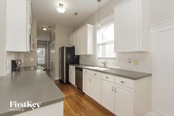 Huntersville house for rent - a kitchen with white cabinets and black appliances and a wood floor