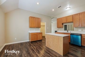 Crosby house for rent - a kitchen with wood flooring and wooden cabinets and a blue dishwasher