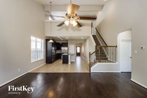 Katy house for rent - A spacious living room with a staircase and a ceiling fan.