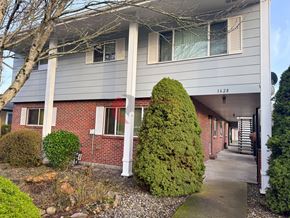 Longview apartment for rent - A grey building with a red brick wall and a white column.