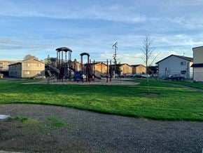 Longview apartment for rent - A playground with a swing set and a tree in the foreground.