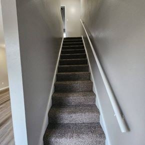 Longview apartment for rent - A staircase with a grey carpeted runner and white handrails.