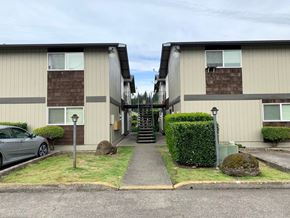 Kelso apartment for rent - A grey car is parked in front of a building with a grey wall and a brown roof.