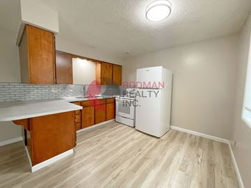 Kelso apartment for rent - A kitchen with wooden cabinets and a Budman Realty Inc. sign.