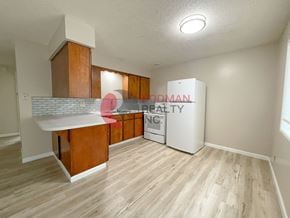 Kelso apartment for rent - A realty sign is on a cabinet in a room with wood flooring.
