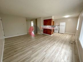 Kelso apartment for rent - A room with wooden flooring and white walls, with a kitchenette in the background.