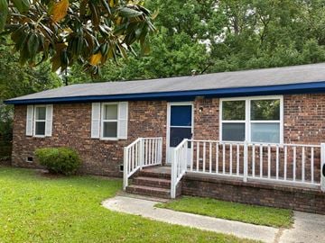 Columbia house for rent - a small brick house with a porch and a blue door