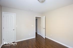 Charlotte house for rent - a bedroom with white walls and wood flooring and a door to a hallway