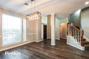 Crosby house for rent - an empty living room with a staircase and a large window