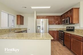 Buckeye house for rent - a kitchen with wooden cabinets and granite counter tops and a stainless steel refrigerator