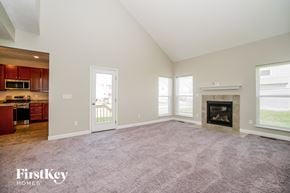 Reynoldsburg house for rent - A spacious living room with a fireplace and a view of the backyard.