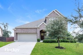 Conroe house for rent - a brick house with a white garage door and a tree