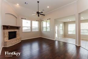 Conroe house for rent - an empty living room with a fireplace and a ceiling fan
