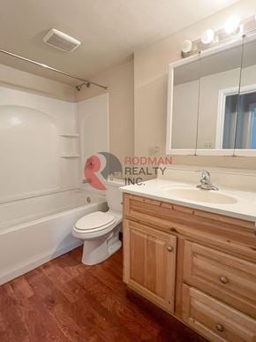Longview house for rent - A white toilet sits in a bathroom with wooden cabinets and a large mirror.