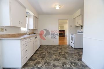 Longview house for rent - A kitchen with white cabinets and a stone floor.
