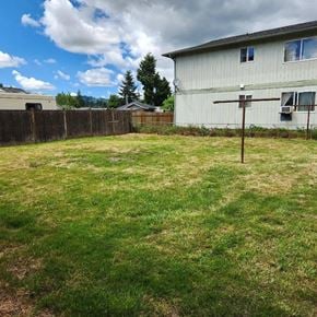 Kelso house for rent - A backyard with a wooden fence and a house in the background.