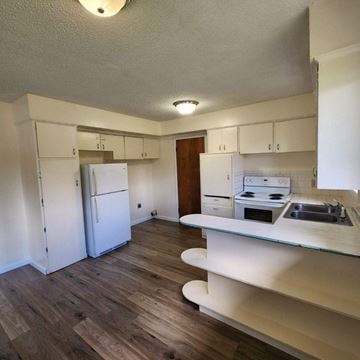 Kelso house for rent - A kitchen with a white fridge and wooden floors.