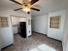 Kelso house for rent - an empty living room with a ceiling fan and a kitchen