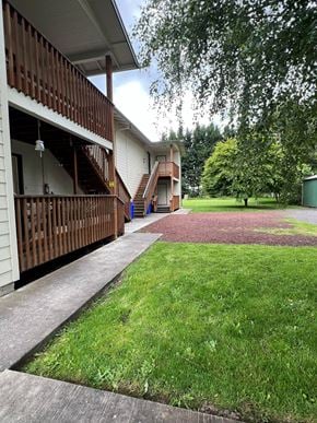 Kelso apartment for rent - A white building with a balcony and a red brick walkway.