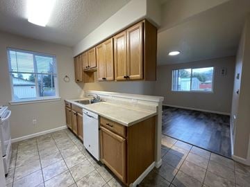 Kelso apartment for rent - A kitchen with wooden cabinets and a white dishwasher.