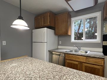 Longview apartment for rent - A kitchen with a white refrigerator and a window with a view of trees outside.