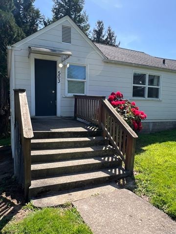 Longview house for rent - A small white house with a black door and a wooden staircase leading to the entrance.