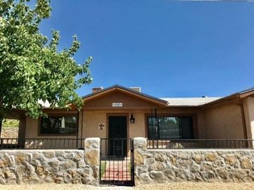 Las Cruces house for rent - a house with a stone wall and a gate