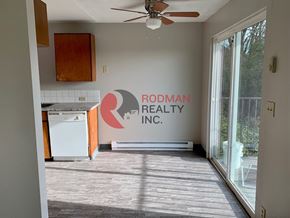 Kelso apartment for rent - A Rodman Realty Inc. logo is on a wall in a room with a ceiling fan.