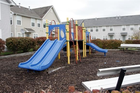 St. Louis apartment for rent - a playground with slides and benches in front of houses