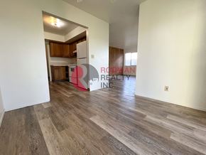 Longview apartment for rent - A room with wooden flooring and a white wall with a doorway leading to another room.