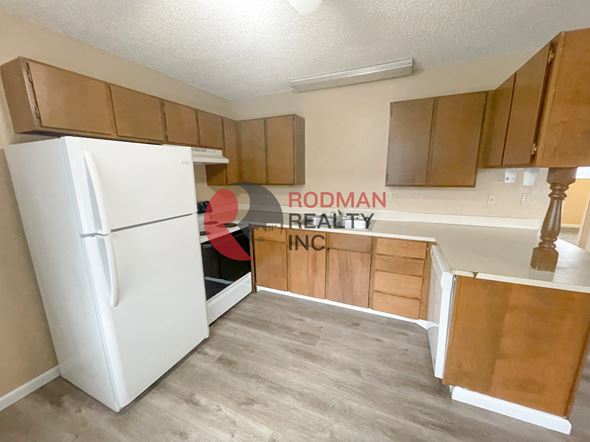Longview apartment for rent - A white refrigerator is in a kitchen with wooden cabinets.