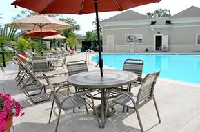 St. Louis apartment for rent - a patio table with chairs and umbrellas next to a pool
