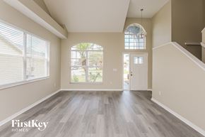Brandon house for rent - A spacious room with wooden floors and a large arched window.
