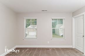 Kernersville house for rent - a bedroom with two windows and a carpeted floor
