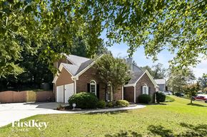 Kennesaw house for rent - A house with a white door and a brick facade is surrounded by greenery.
