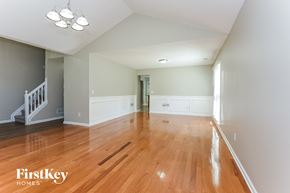 Kennesaw house for rent - A spacious room with wooden floors and a staircase on the left side.