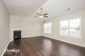 Winston Salem house for rent - an empty living room with a ceiling fan and a fireplace
