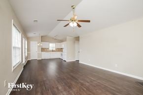 Winston Salem house for rent - an empty living room with a ceiling fan and a kitchen