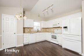Winston Salem house for rent - a kitchen with white cabinets and white appliances and wood floors