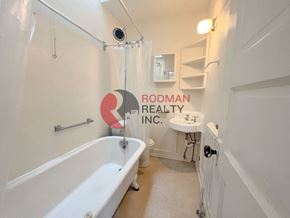 Kelso apartment for rent - A bathroom with a bathtub, sink, and a Rodman Realty Inc. logo.