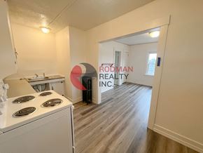 Kelso apartment for rent - A small, clean, and empty apartment with a stove and a sign that says Rodman Realty Inc.