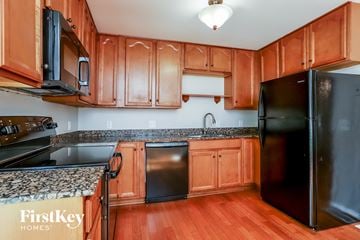 St Peters house for rent - a kitchen with wood cabinets and black appliances and granite counter tops
