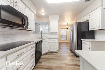 Plano house for rent - A kitchen with white cabinets and black appliances.