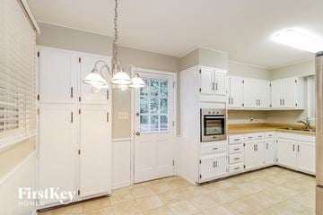 Greensboro house for rent - a large white kitchen with white cabinets and a window