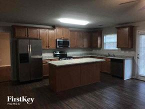 Charlotte house for rent - a kitchen with wooden cabinets and a stainless steel refrigerator
