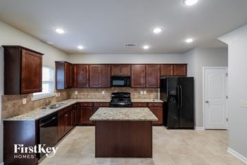Winder house for rent - a kitchen with wooden cabinets and granite counter tops and a black refrigerator